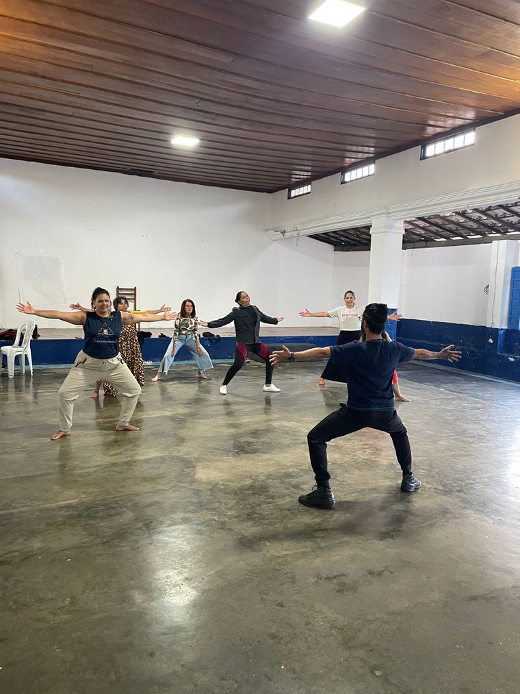 Grupo em movimento durante a vivência de dançaterapia em um salão