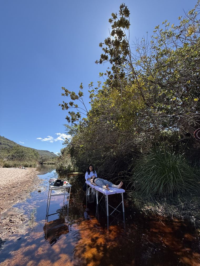 Maca montada às margens do Rio Mucugê, entre a vegetação, com a Chapada ao fundo