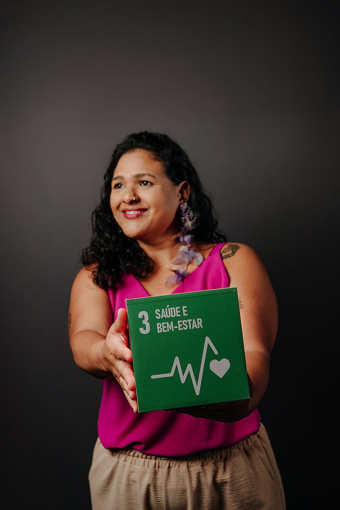 Jardim, idealizadora e anfitriã, segurando um cubo verde do ODS 3 Saúde e Bem-Estar