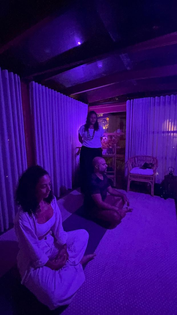 Ambiente da tenda com luz violeta e participantes em meditação